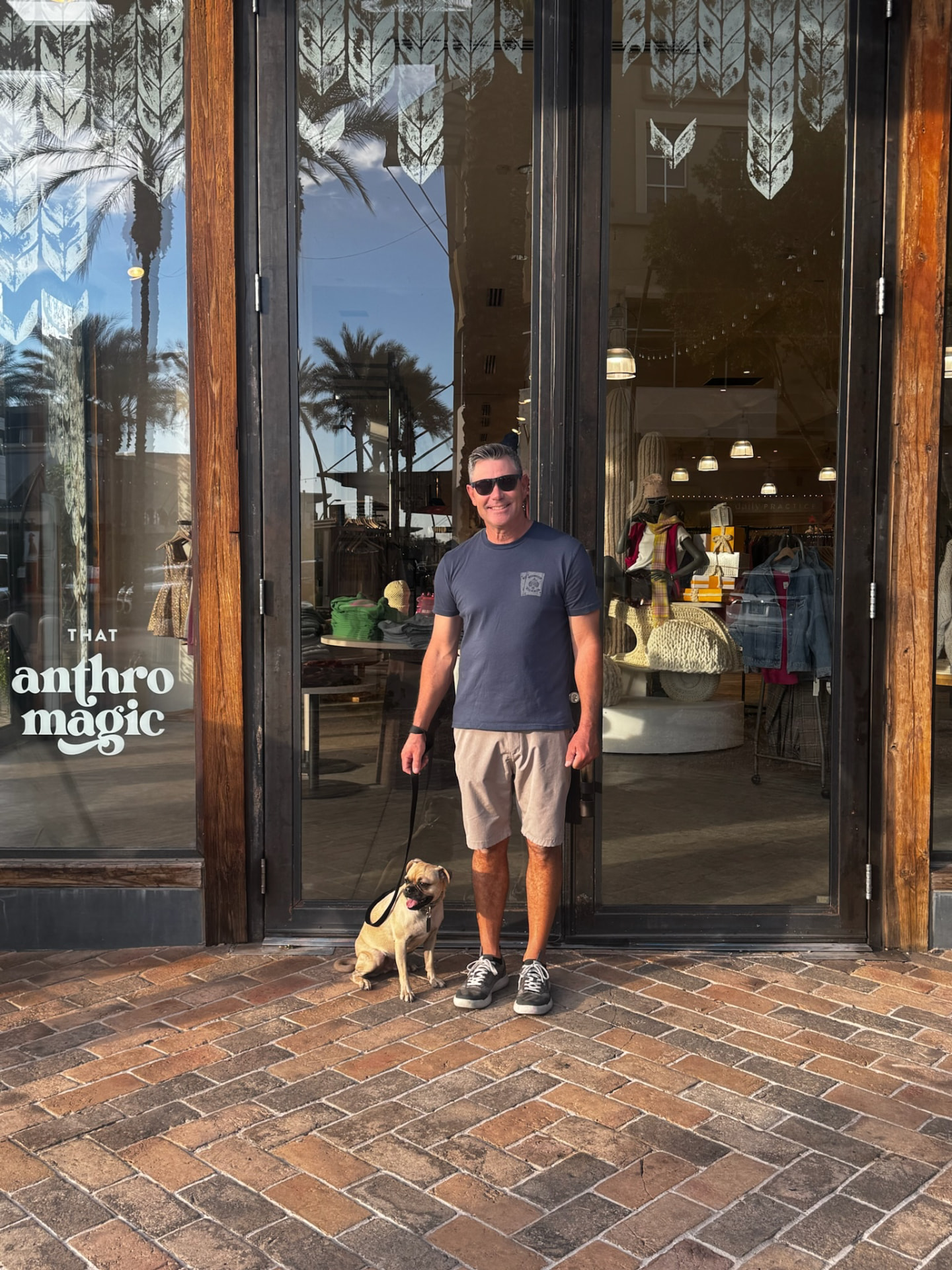 Client and his dog holding a calm sit outside a shop
