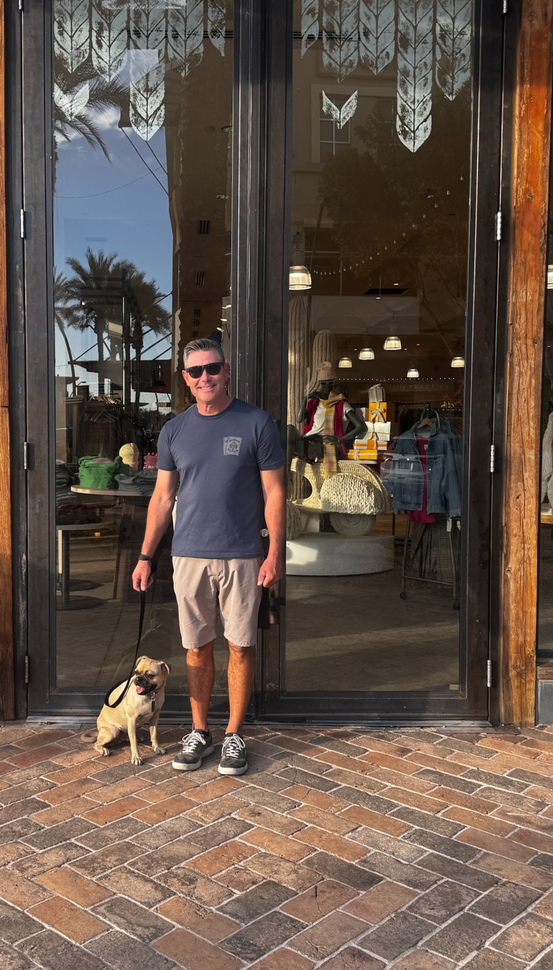 Client and his dog holding a calm sit-stay outside a busy storefront